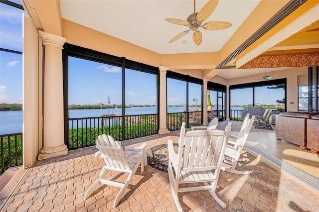 sunroom / solarium featuring ceiling fan, a water view, ornate columns, and plenty of natural light