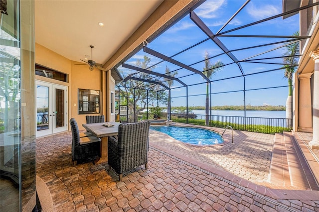 view of swimming pool featuring ceiling fan, a water view, glass enclosure, a patio, and a hot tub