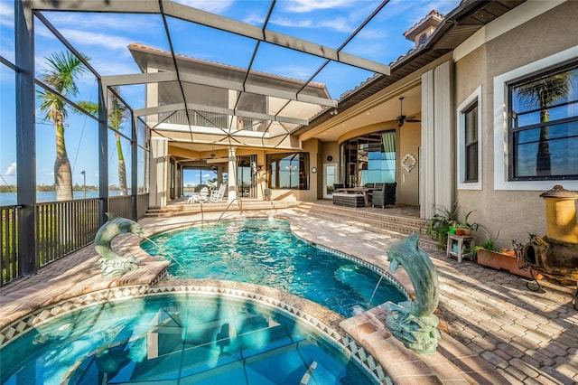 view of swimming pool featuring glass enclosure, a water view, pool water feature, ceiling fan, and a patio