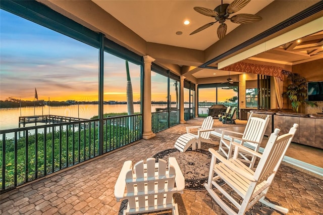 patio terrace at dusk with a water view and ceiling fan