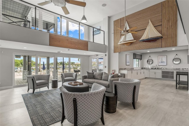 living room with a wealth of natural light, sink, ceiling fan, and a high ceiling