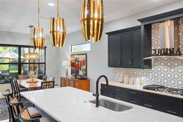 kitchen with a breakfast bar, sink, tasteful backsplash, hanging light fixtures, and light stone countertops