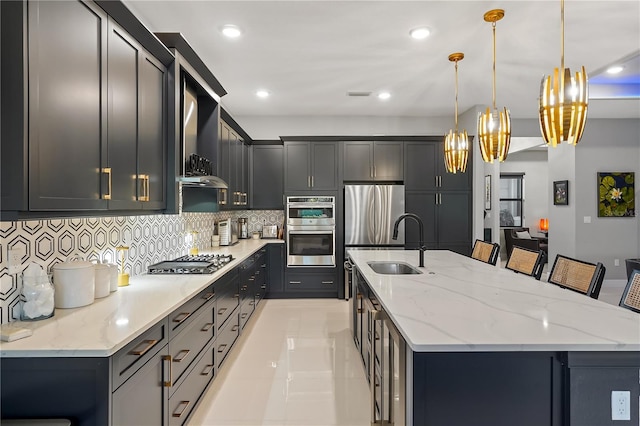 kitchen with a center island with sink, pendant lighting, a breakfast bar area, and appliances with stainless steel finishes