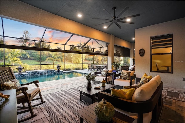 pool at dusk with a lanai, an outdoor hangout area, ceiling fan, and a patio area