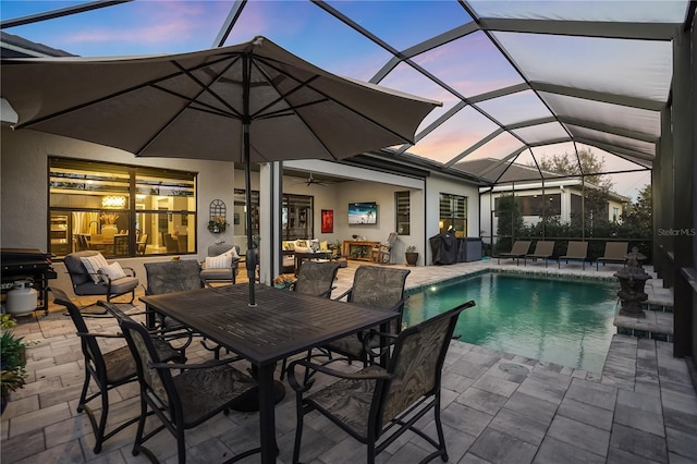 pool at dusk with a lanai, a patio, and ceiling fan