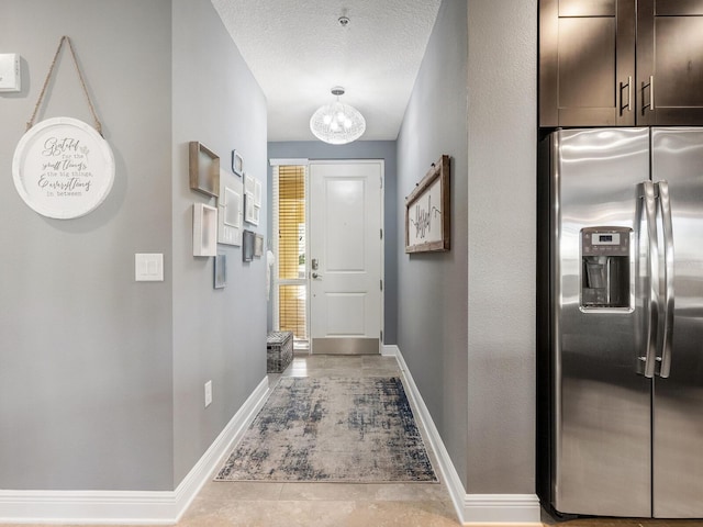 corridor featuring light tile patterned floors, a textured ceiling, and a notable chandelier