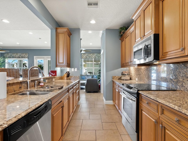 kitchen featuring sink, decorative backsplash, ceiling fan, light stone countertops, and stainless steel appliances