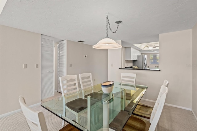 carpeted dining area featuring ceiling fan and a textured ceiling