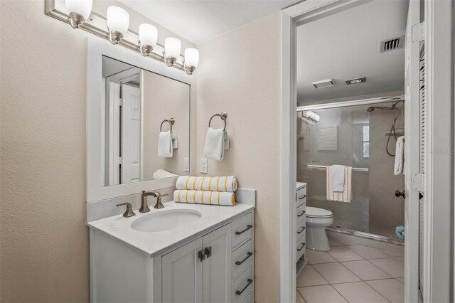 bathroom with tile patterned floors, vanity, toilet, and a shower with shower door