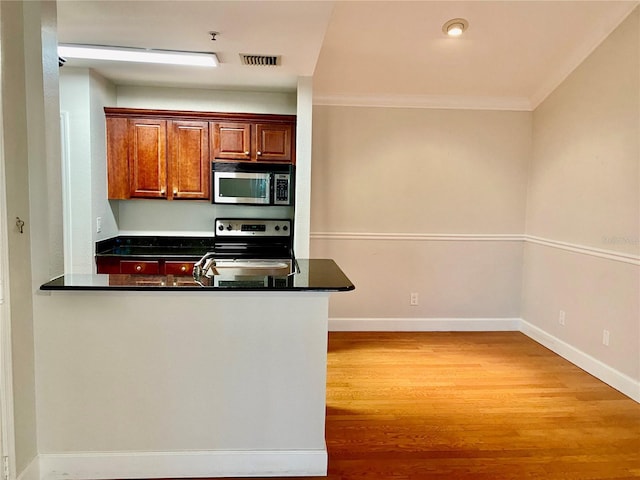 kitchen with kitchen peninsula, stainless steel appliances, light hardwood / wood-style flooring, and ornamental molding