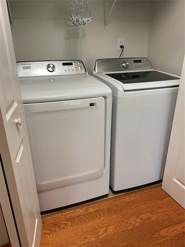 laundry room with washer and dryer and light wood-type flooring