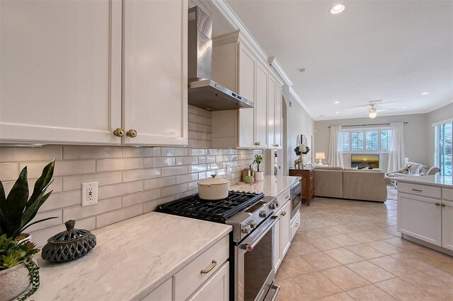 kitchen with white cabinets, high end range, open floor plan, light stone countertops, and wall chimney range hood