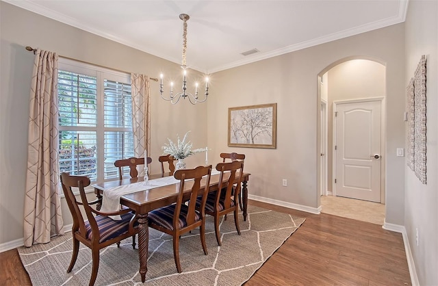 dining room with arched walkways, baseboards, dark wood-style floors, and crown molding