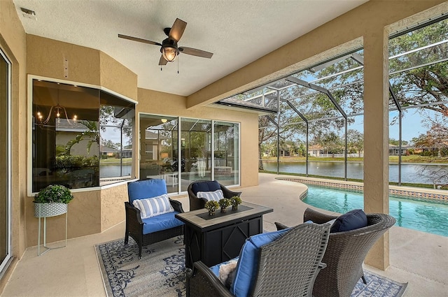 sunroom featuring ceiling fan and a water view