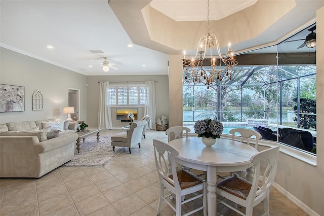 dining room with a raised ceiling, ornamental molding, a sunroom, light tile patterned flooring, and ceiling fan