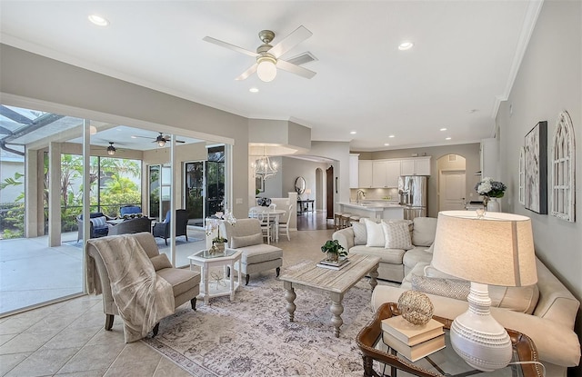 living room with recessed lighting, visible vents, arched walkways, ornamental molding, and ceiling fan with notable chandelier