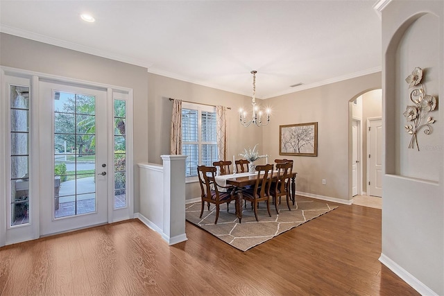 dining space featuring arched walkways, ornamental molding, wood finished floors, and baseboards