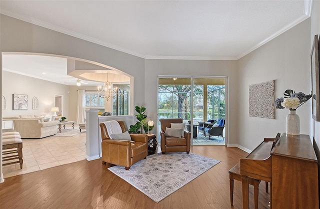 sitting room featuring arched walkways, plenty of natural light, and light wood-style flooring