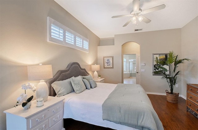 bedroom featuring arched walkways, ensuite bathroom, dark wood-type flooring, visible vents, and baseboards