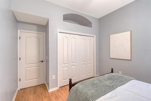 bedroom featuring light wood finished floors, a closet, and baseboards