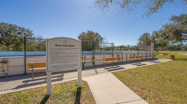 view of property's community with a tennis court, a lawn, and fence