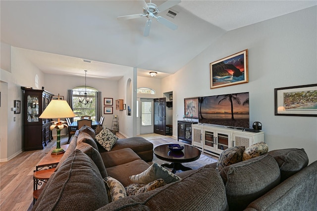 living room featuring ceiling fan with notable chandelier, lofted ceiling, and light hardwood / wood-style flooring