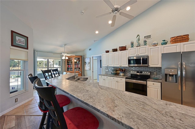 kitchen featuring white cabinets, a kitchen breakfast bar, stainless steel appliances, and decorative backsplash