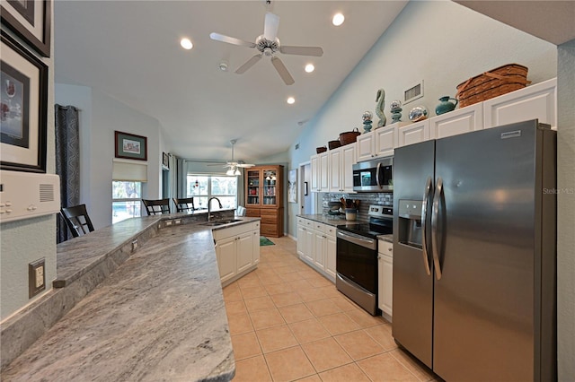 kitchen featuring appliances with stainless steel finishes, sink, high vaulted ceiling, white cabinetry, and light tile patterned flooring