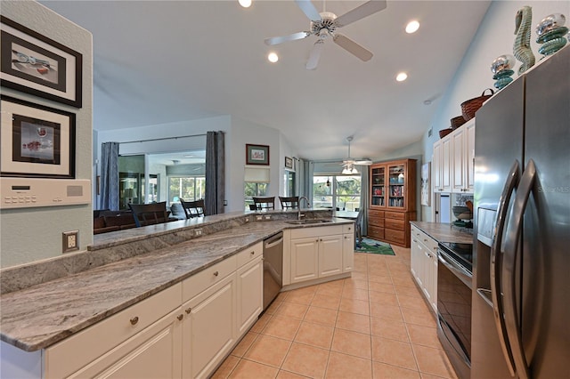 kitchen with appliances with stainless steel finishes, vaulted ceiling, sink, white cabinetry, and light tile patterned flooring