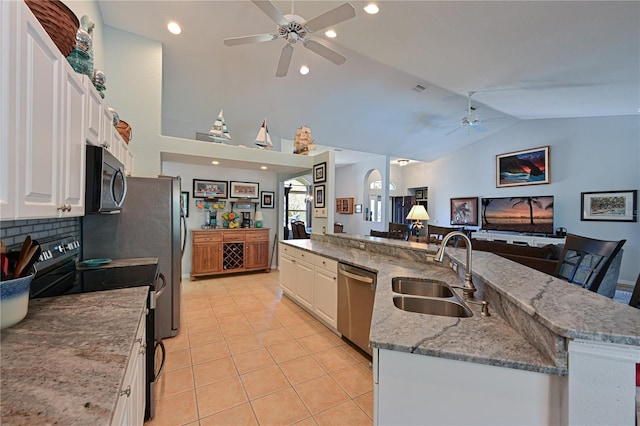 kitchen with a large island with sink, sink, vaulted ceiling, white cabinetry, and stainless steel appliances