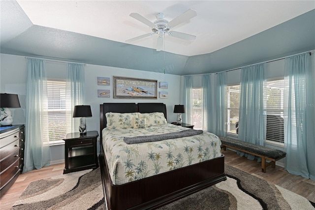 bedroom featuring multiple windows, ceiling fan, vaulted ceiling, and light wood-type flooring