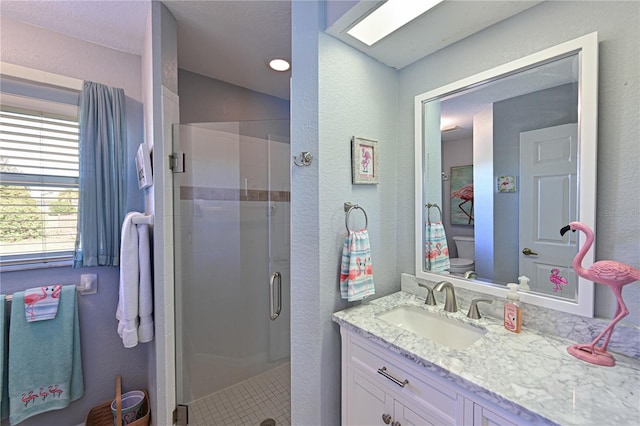 bathroom with an enclosed shower, vanity, toilet, and a skylight