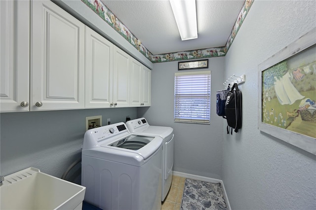 laundry room featuring cabinets, a textured ceiling, washer and clothes dryer, sink, and light tile patterned flooring