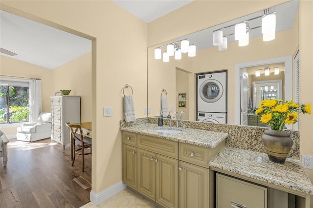 bathroom featuring hardwood / wood-style floors, vanity, stacked washer / dryer, and vaulted ceiling