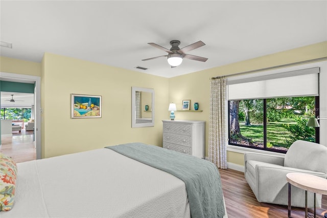 bedroom featuring ceiling fan, light wood-type flooring, and multiple windows