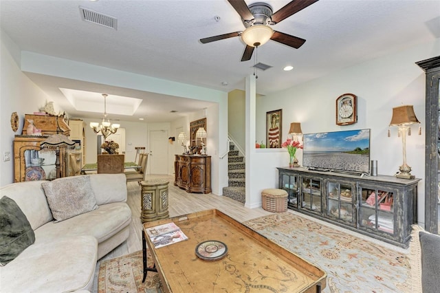 living room featuring a textured ceiling, ceiling fan with notable chandelier, and light wood-type flooring