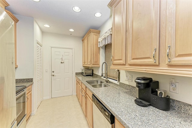 kitchen featuring sink, light tile patterned floors, light brown cabinetry, appliances with stainless steel finishes, and light stone counters