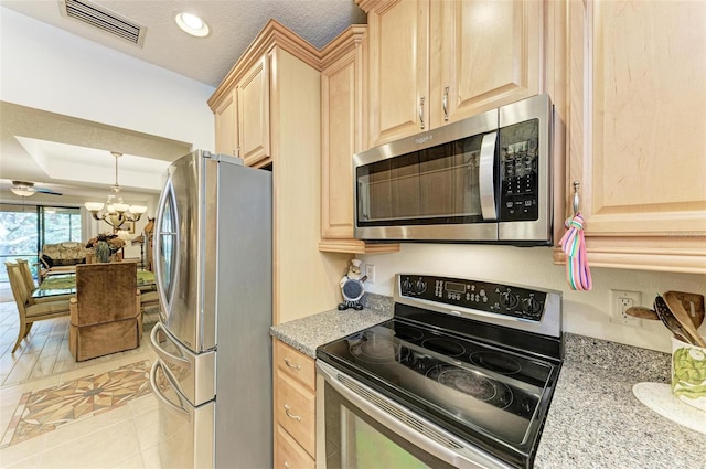 kitchen featuring a textured ceiling, stainless steel appliances, light brown cabinets, light tile patterned floors, and a notable chandelier