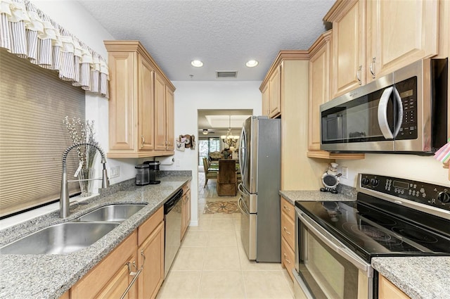 kitchen with light brown cabinetry, sink, light tile patterned floors, and stainless steel appliances