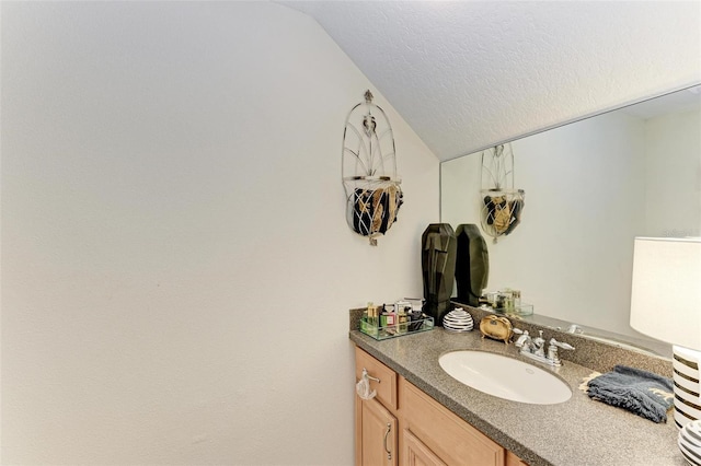 bathroom featuring a textured ceiling, vanity, and lofted ceiling