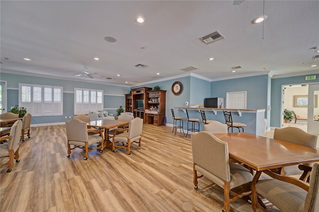 dining space featuring a textured ceiling, light hardwood / wood-style flooring, ceiling fan, and crown molding