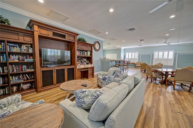 living room featuring light hardwood / wood-style flooring, ceiling fan, and crown molding