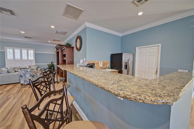 kitchen featuring light stone countertops, sink, stainless steel fridge with ice dispenser, crown molding, and light wood-type flooring