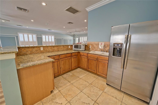 kitchen with kitchen peninsula, stainless steel fridge, plenty of natural light, and light stone counters