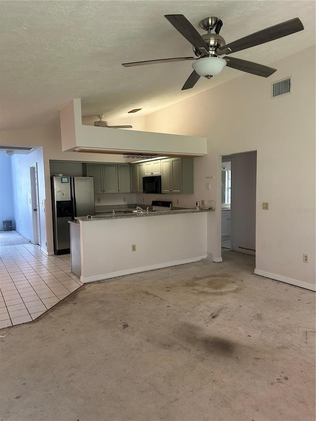 kitchen with stone counters, light tile patterned flooring, stainless steel fridge, and kitchen peninsula