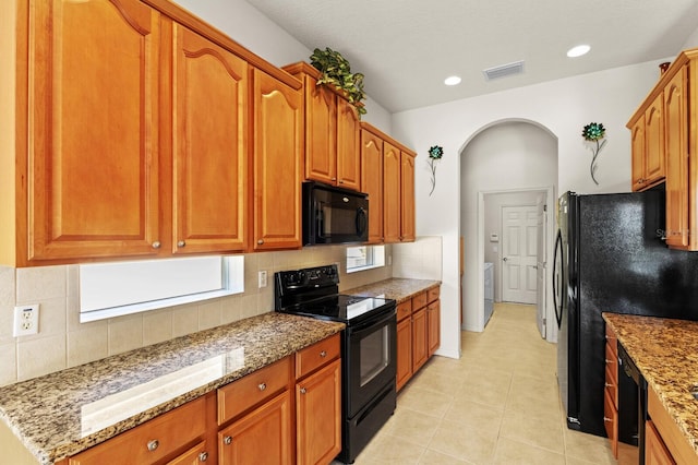 kitchen with light stone countertops, tasteful backsplash, a wealth of natural light, and black appliances