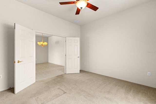 carpeted spare room with ceiling fan with notable chandelier