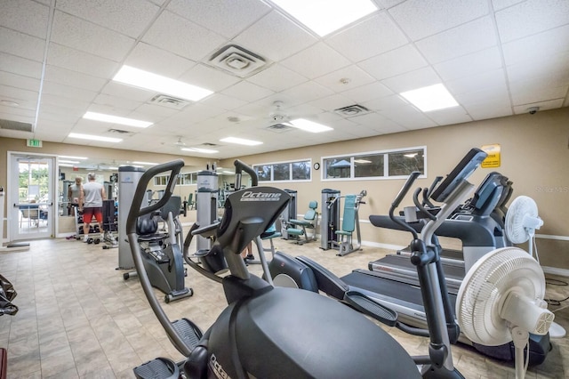 exercise room with ceiling fan and a drop ceiling