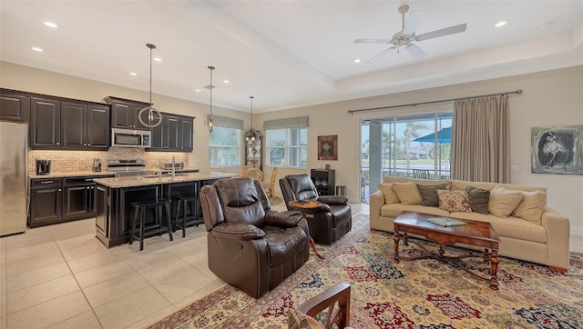 living room with ceiling fan, light tile patterned flooring, and a tray ceiling