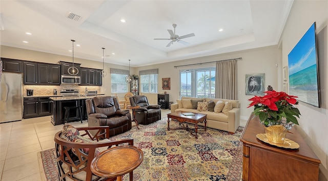 tiled living room with a tray ceiling and ceiling fan